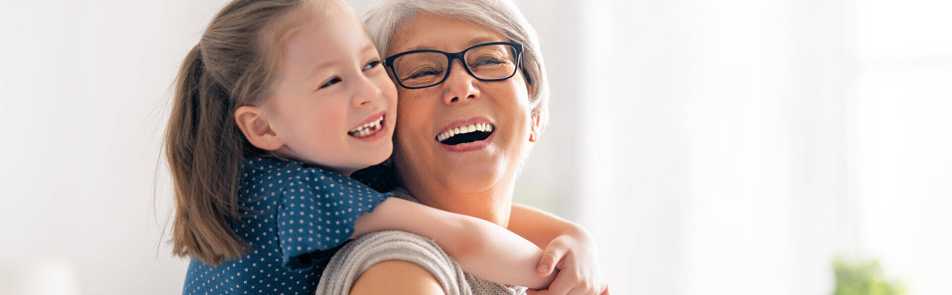 A child hugging her grandma and them both smiling.