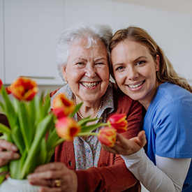 Older woman and younger woman smiling together with flowers